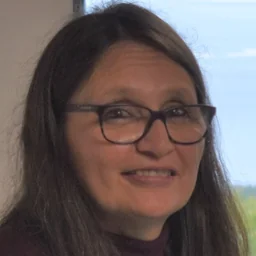 Arlene Lehto, founder of Circle Bound Strategies, smiling beside a hand-painted paddle